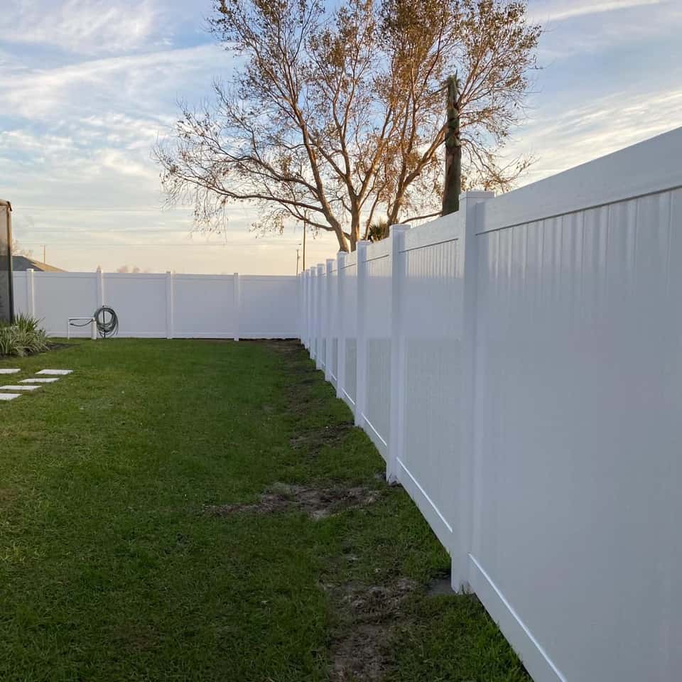 White vinyl privacy fence enclosing a large backyard lawn — Lobo Fences LLC, Southwest Florida