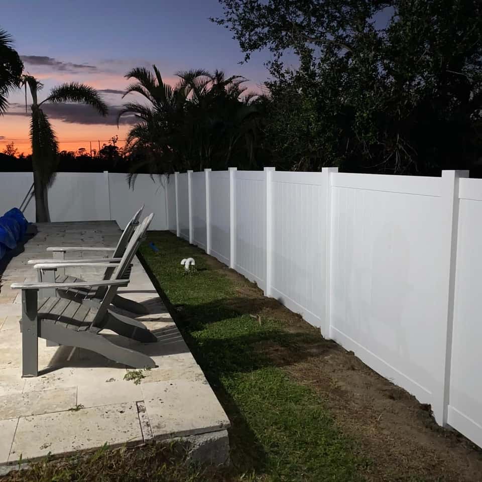 White vinyl privacy fence beside a paver patio at sunset — Lobo Fences LLC, Southwest Florida