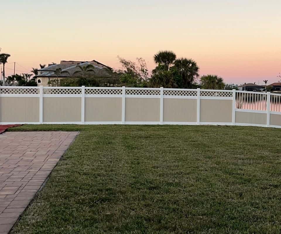 Tan vinyl privacy fence with white lattice topper facing a canal at dusk — Lobo Fences LLC, Southwest Florida