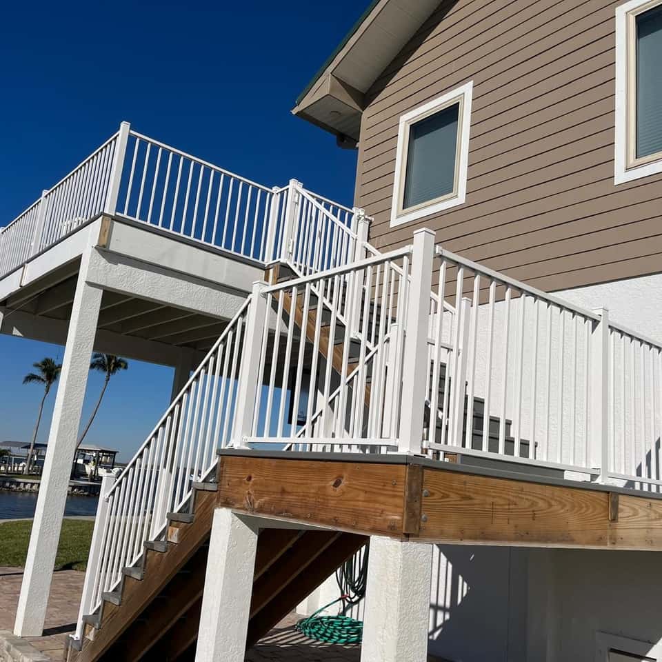 White aluminum deck railing on an elevated waterfront deck and staircase — Lobo Fences LLC, Southwest Florida