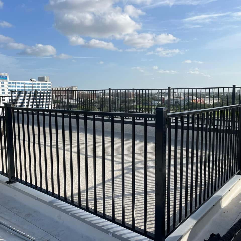 Black aluminum railing enclosing a rooftop terrace with a city skyline behind it — Lobo Fences LLC, Southwest Florida