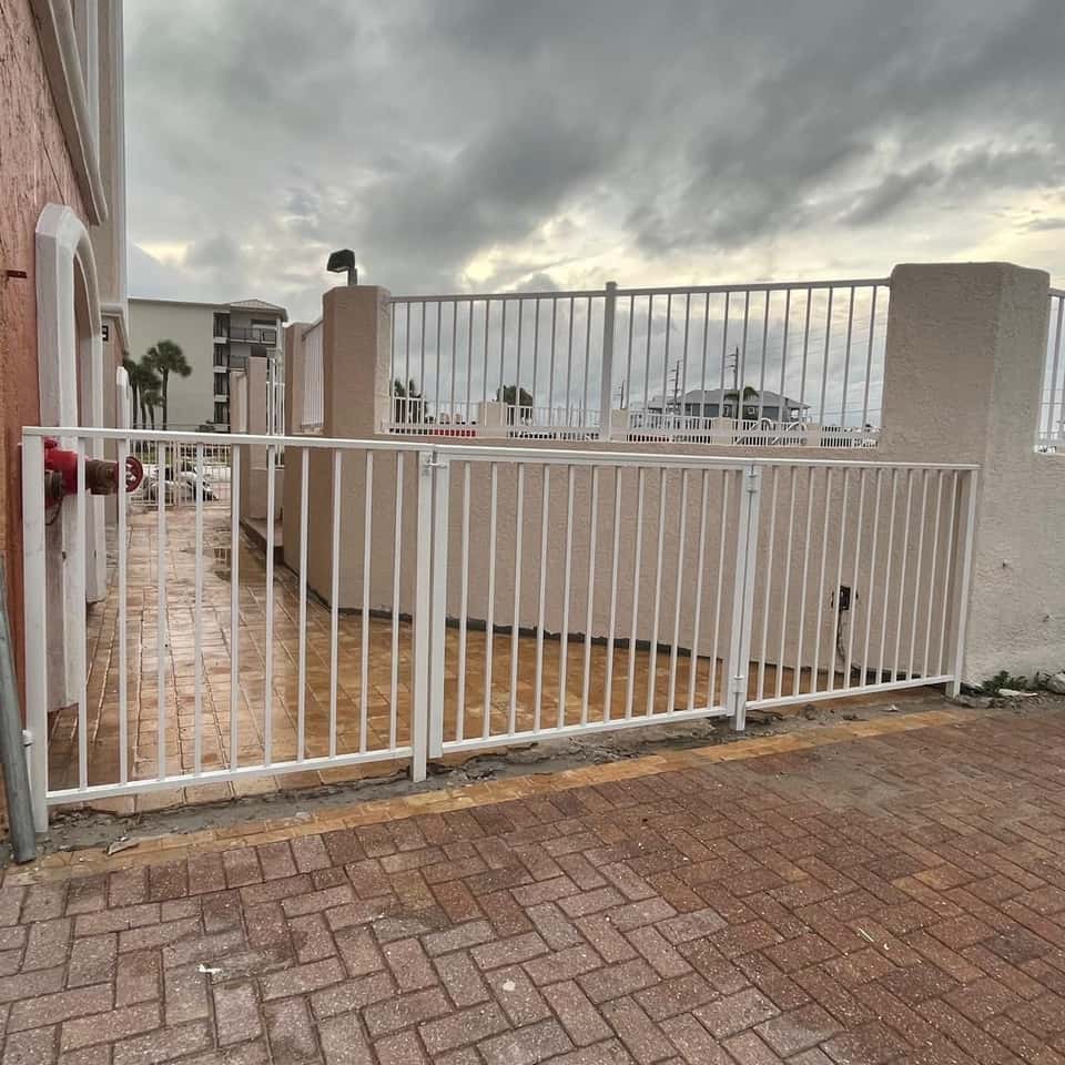 White aluminum fence and gate on a paver driveway at a waterfront property — Lobo Fences LLC, Southwest Florida
