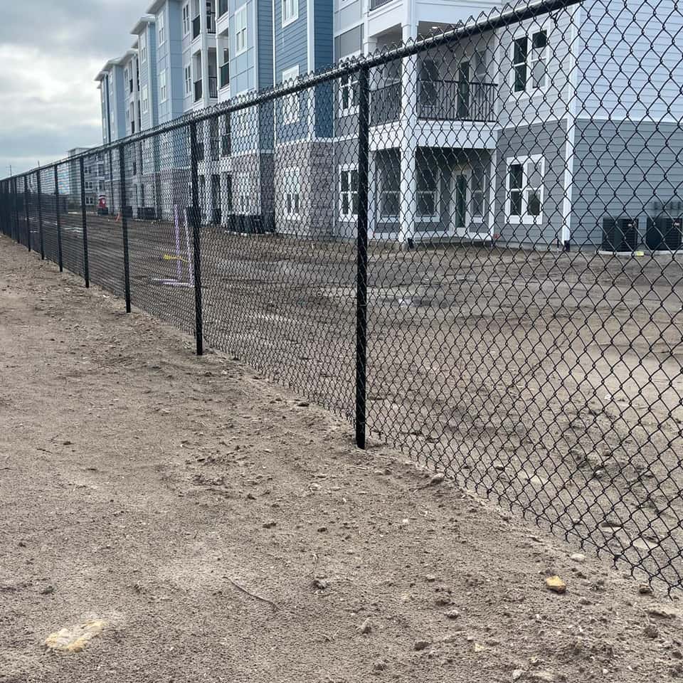 Black chain link fence securing a construction site next to an apartment building — Lobo Fences LLC, Southwest Florida