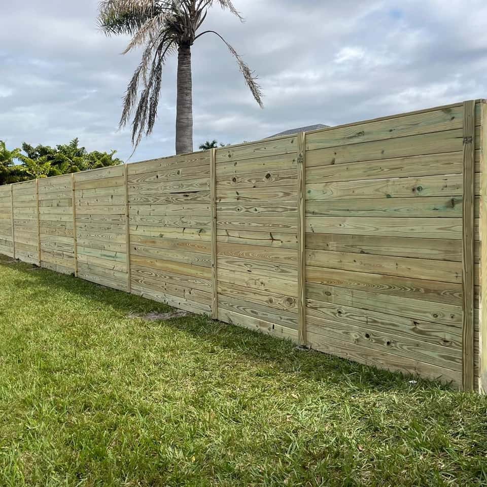 Horizontal wood privacy fence panels in a palm-shaded backyard — Lobo Fences LLC, Southwest Florida