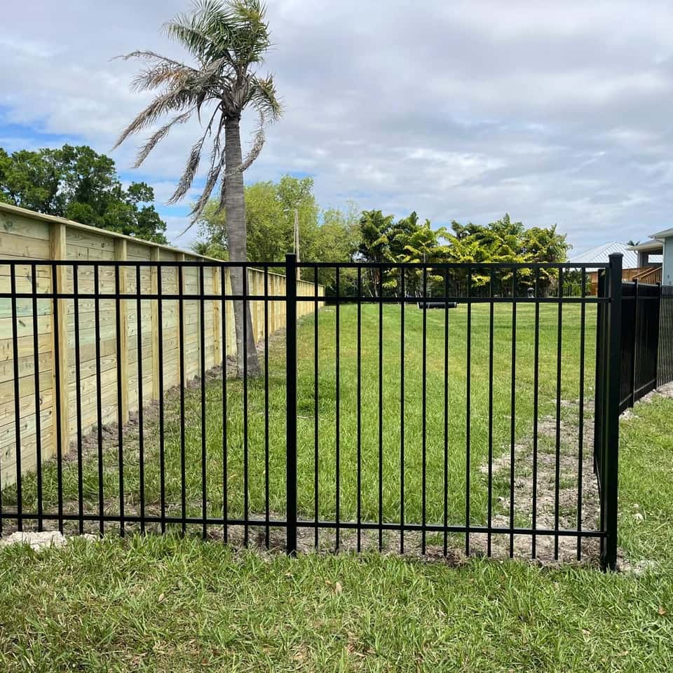 Black aluminum fence with a horizontal wood privacy fence behind it — Lobo Fences LLC, Southwest Florida